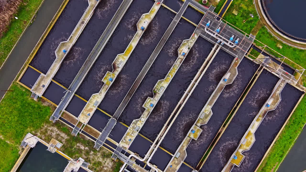 Several large water treatment tanks in a facility with pipes and equipment visible during daytime