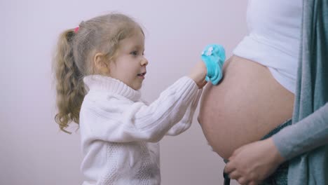 pretty girl touches pregnant mom belly with blue booties