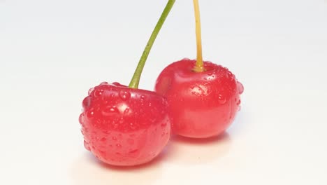 macro video, two juicy bright red cherries, fresh tasty berries on a white background, rotation of red berries