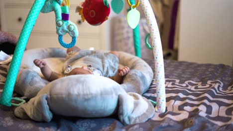 delightful curious newborn baby in cradle staring at toys above