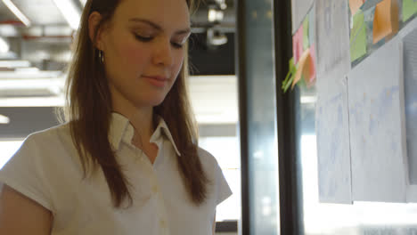 front view of young caucasian businesswoman using digital tablet and working on glass wall 4k