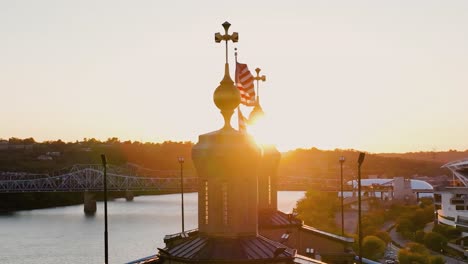 aerial view around a us flag waving in front of the ohio river, sunset in usa - slow motion, orbit, drone shot