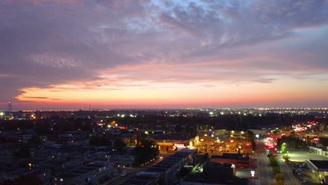 Toma-Aérea-De-Drones-Del-Vibrante-Cielo-Crepuscular-Mientras-Las-Luces-Del-Paisaje-Urbano-Iluminan-El-Horizonte,-Montreal,-Canadá