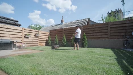 gardener laying a roll of natural lawn turf