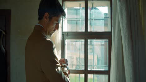 man checking his watch by a window