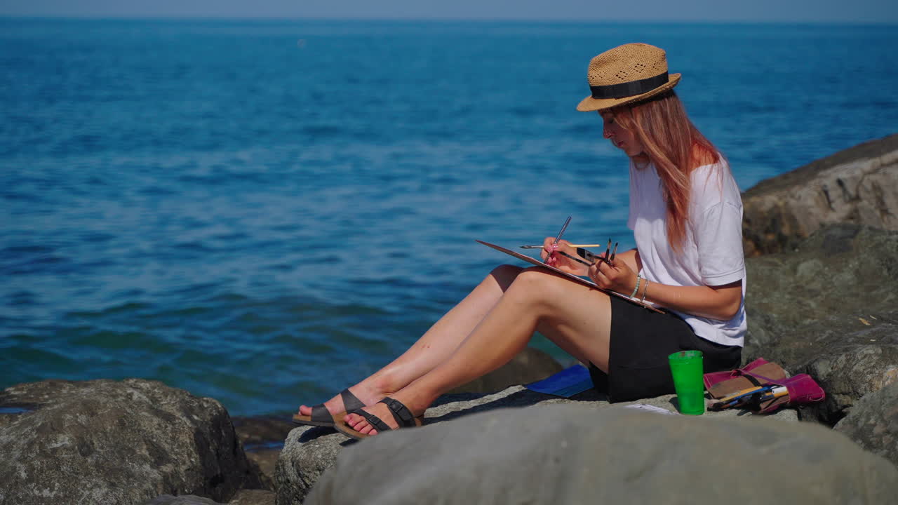 женщина рисует морской пейзаж на пляже