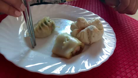 Time-lapse-of-someone-eating-delicious-yum-cha-with-a-pair-of-steel-chopsticks-off-a-white-plate-on-a-red-table-mat