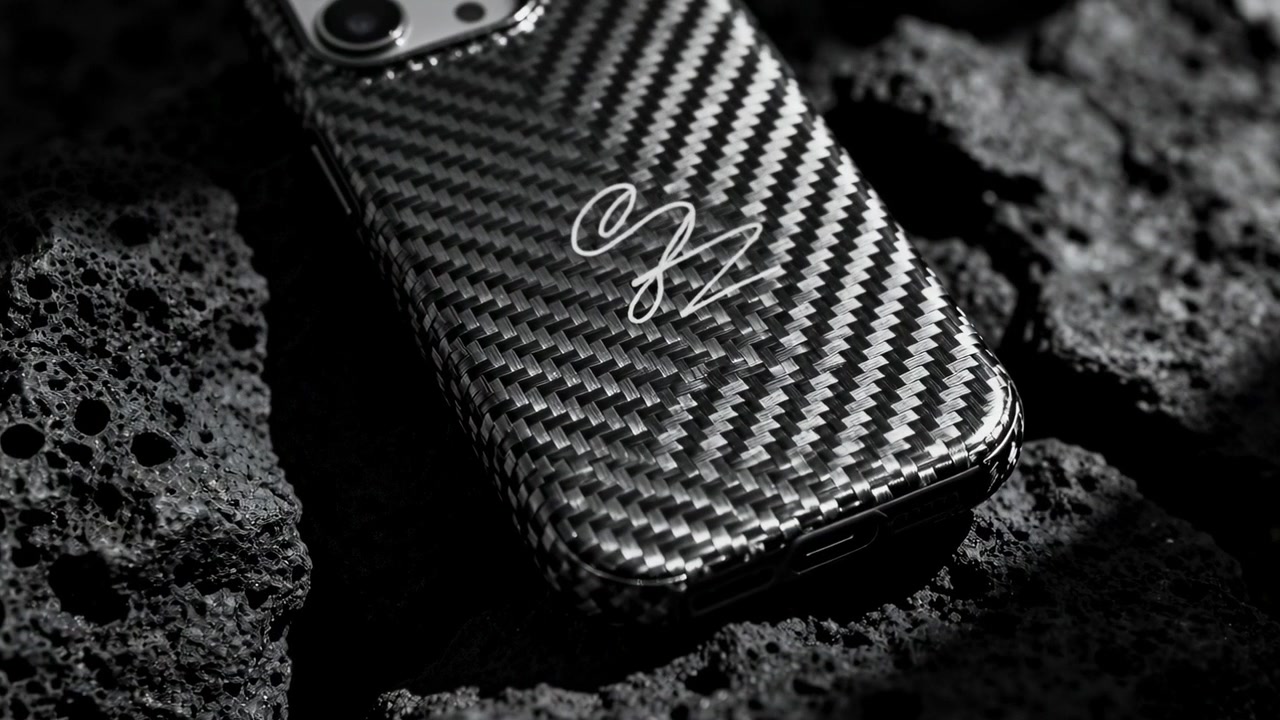 Luce cangiante che rivela uno smartphone con custodia in carbonio, doppia fotocamera e porta su una superficie di pomice.