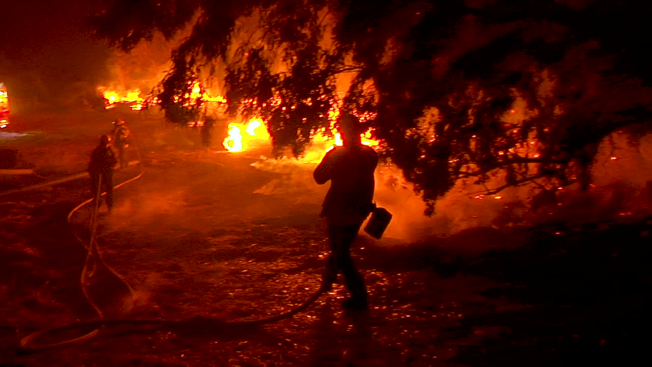 캘리포니아 벤투라 카운티의 토마스 화재 동안 통제 불능으로 타오르는 덤불 화재를 진압하기 위해 소방관들이 열심히 일하고 있습니다.