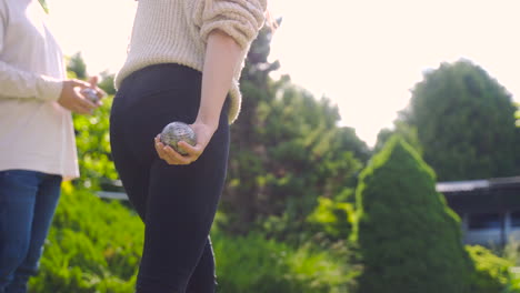 Rückansicht-Einer-Kaukasischen-Jungen-Frau,-Die-An-Einem-Sonnigen-Tag-Einen-Pétanque-Ball-Im-Park-Wirft