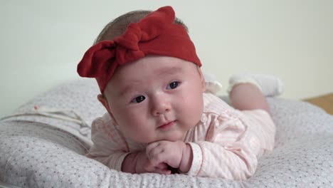 newborn infant baby girl lying on belly supporting her head with hands, back and neck training