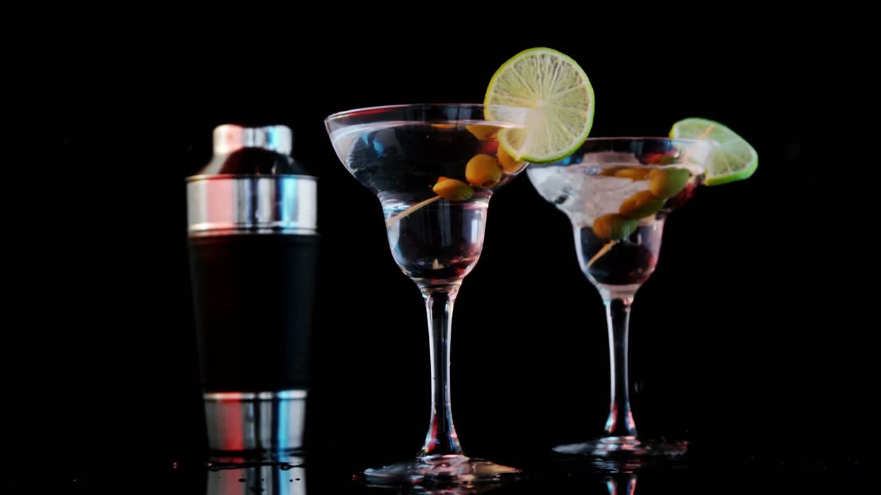 un cubo de hielo cayendo en dos copas de cóctel