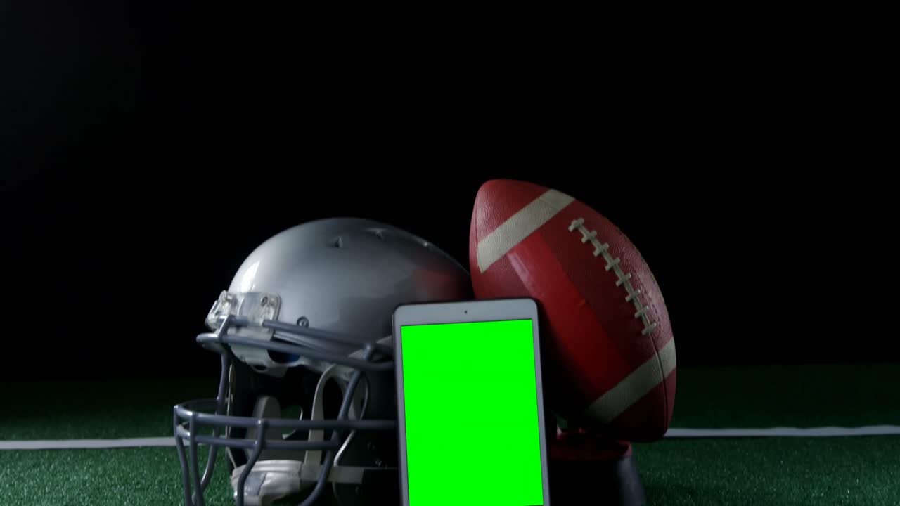Primo piano di pallone, telefono cellulare e casco su campo in erba sintetica 4k