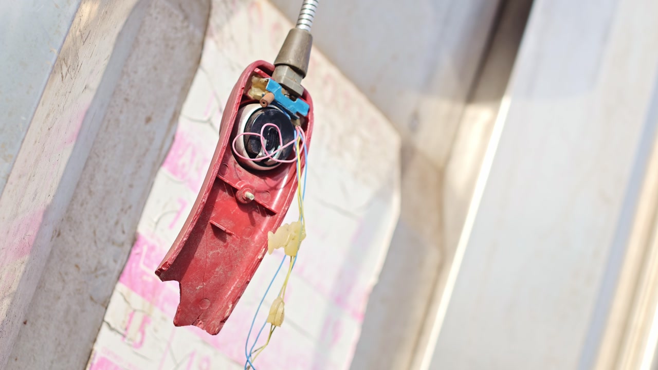Shattered phone receiver sways with wind in slanted view of urban neglect