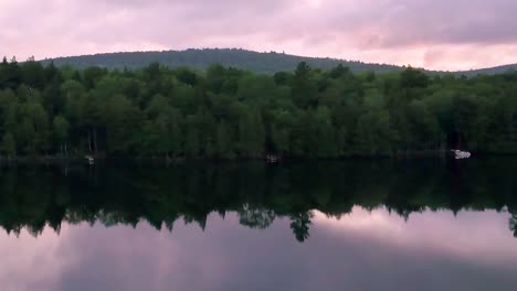 DRONE-SLIDE-along-shore-while-zooming-out,-Monson-Pond,-Maine,-Sunset