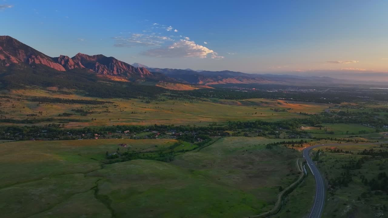 Flatirons Front Range Boulder Chautauqua Park morning sunrise aerial drone Colorado spring summer pink cloud first light on red slanted Rocky Mountains highway 36 car traffic backwards motion
