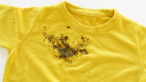 a yellow shirt with a mud stain