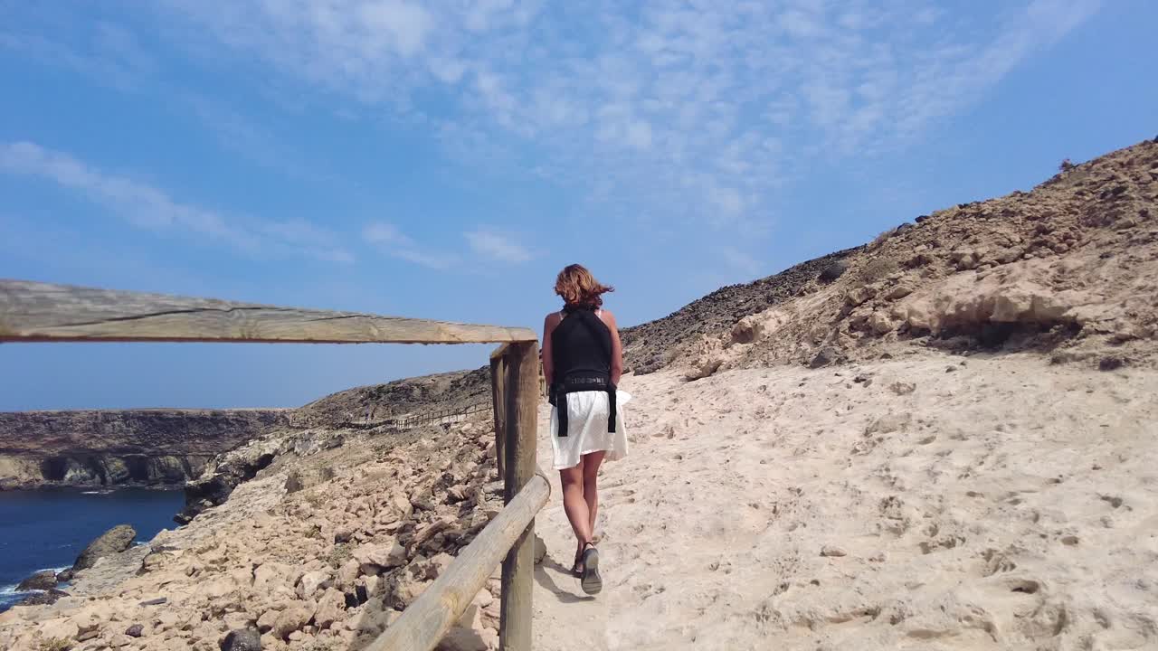 Donna che cammina su un sentiero sabbioso vicino alla costa