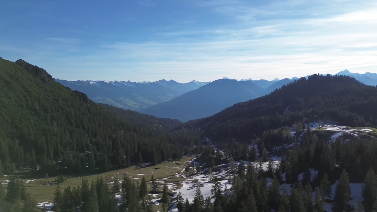 Volo di drone sopra una foresta nelle Alpi austriache circondata da montagne, Austria, Europa.