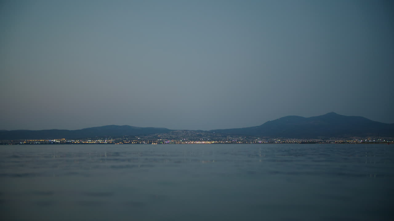 먼 빛과 산악 배경으로 해안 도시 위의 황혼