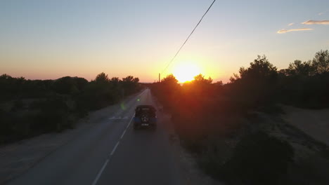 Disparo-De-Un-Dron-Siguiendo-A-Un-Automóvil-Que-Circulaba-Por-Una-Carretera-Entre-árboles