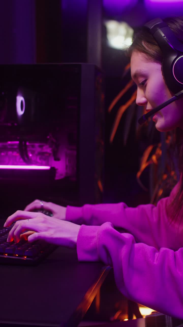 Teenage girl gamer playing video games with headset in neon lit room