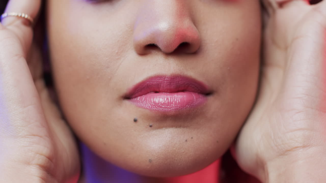 primer plano de una mujer biracial con cabello rizado oscuro en luz azul y rosa, cámara lenta