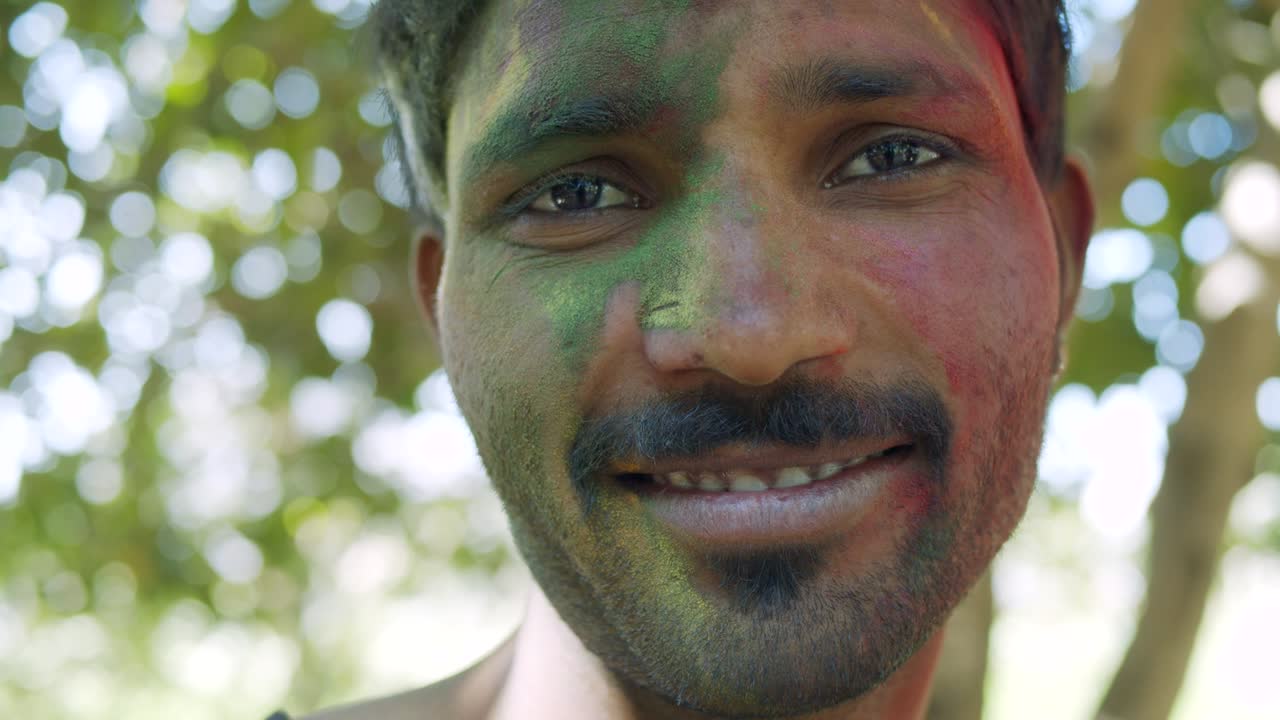 Indian man close-up of face smeared with bright Holi colors