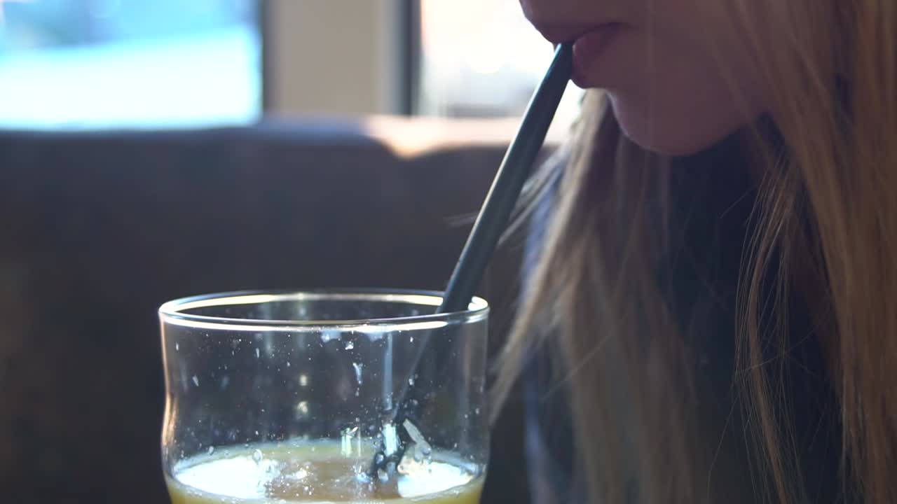Una chica bebiendo jugo de naranja.