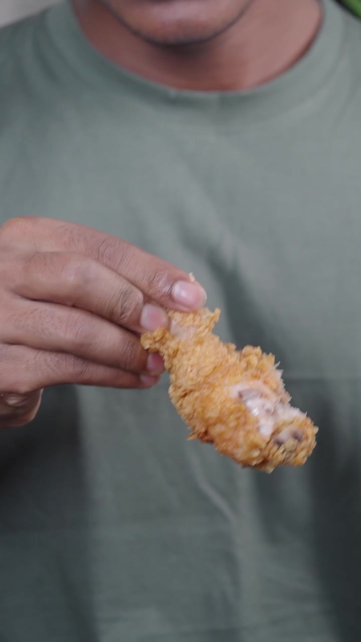 Person Holding a Piece of Crispy Fried Chicken