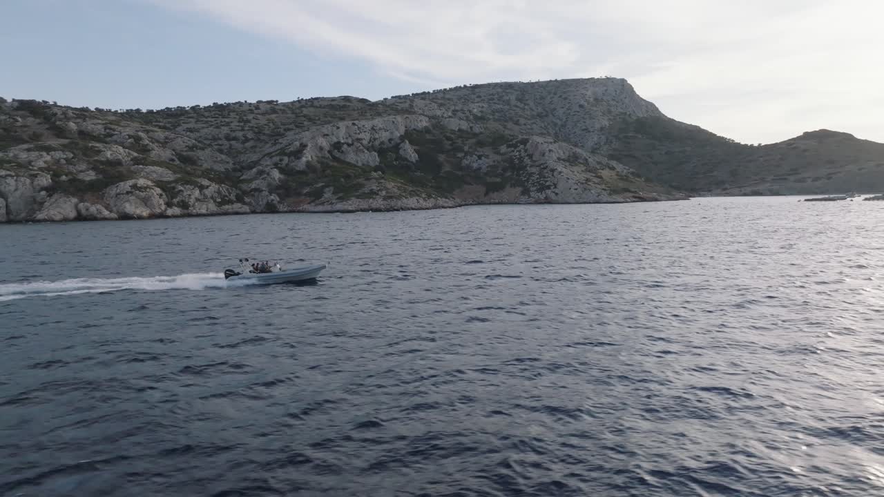 Ripresa aerea in movimento di un motoscafo e una gabbia da pesca al tramonto in Grecia
