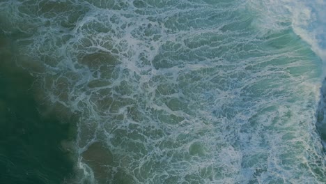 Moody-ocean-textures-created-by-powerful-crashing-waves,-drone-top-down-shot