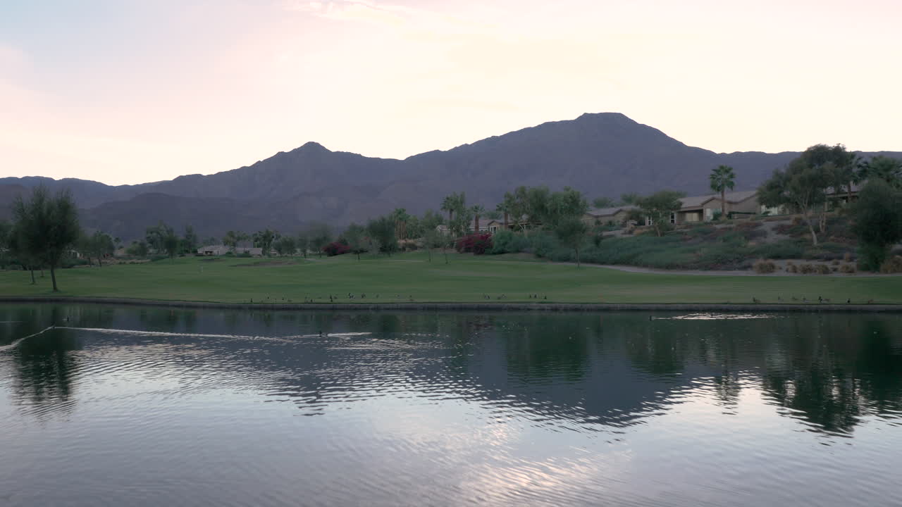 Tranquil Lake Reflection of Mountains and Golf Course at Sunset