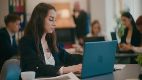 una joven mujer de negocios usando una computadora portátil en la oficina.