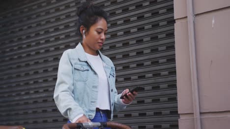 Mixed-race-woman-walking-next-to-her-bike-on-the-street