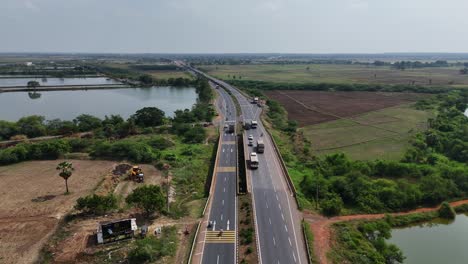 a cinematic aerial shot captures the less traffic on the pristine chennai-vijayawada highway, with towering high-voltage power lines casting long, dramatic shadows across the gleaming black asphalt.