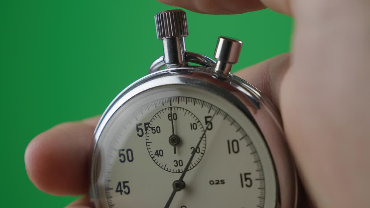 Male hand holding analogue stopwatch on green screen chroma key. Time start with old chronometer man presses start button in the sport concept. Time management concept.