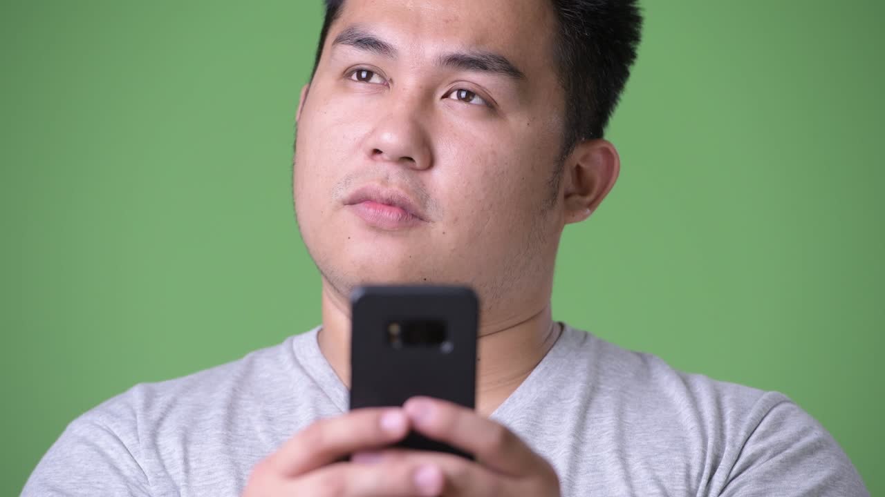 초록색 배경에 젊은 잘생긴 과체중 아시아인