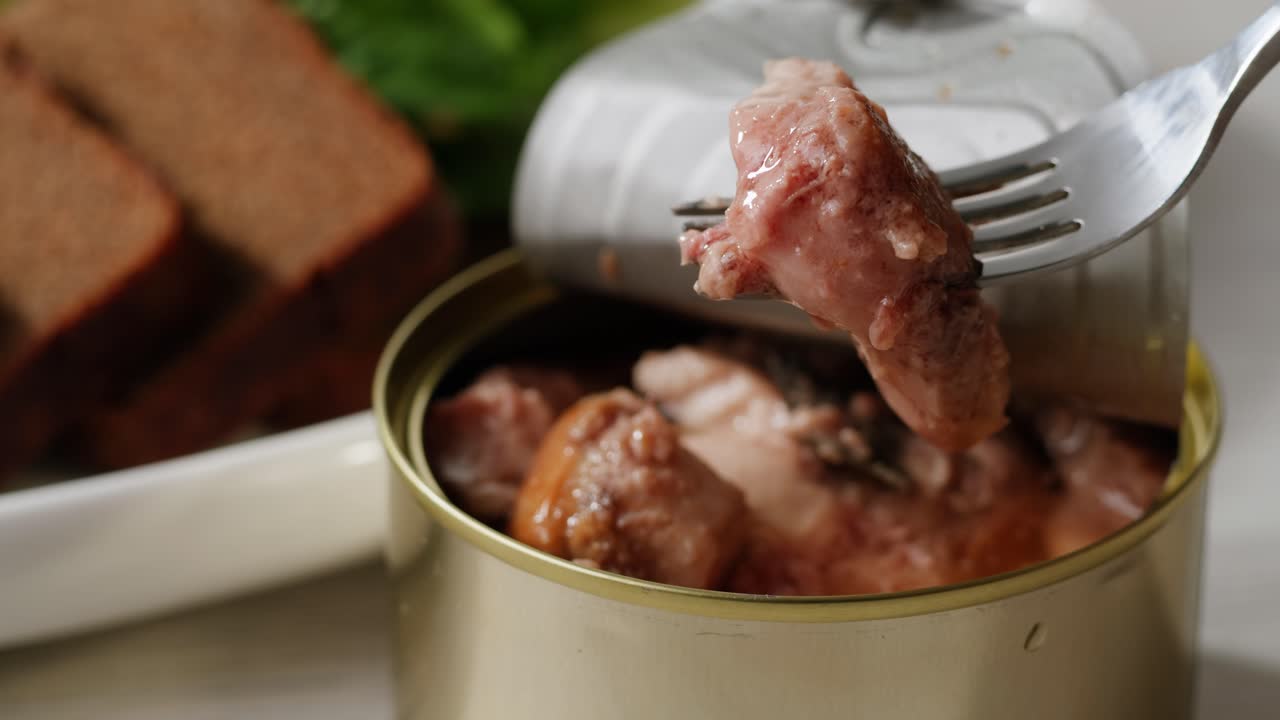 Smoked cod liver in oil in open tin can with fresh greens on wooden table. Seafoods delicacy. High quality 4k footage