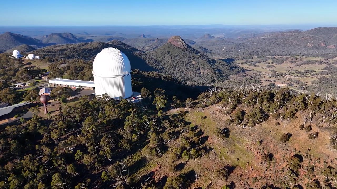 Toma aérea amplia de la cúpula del telescopio del Observatorio Siding Spring en la cima de las montañas del Parque Nacional Warrumbungle