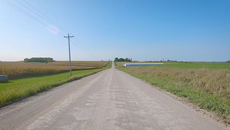 POV-while-driving-on-a-gravel-country-road-towards-a-large-barn-in-rural-Iowa-in-late-summer