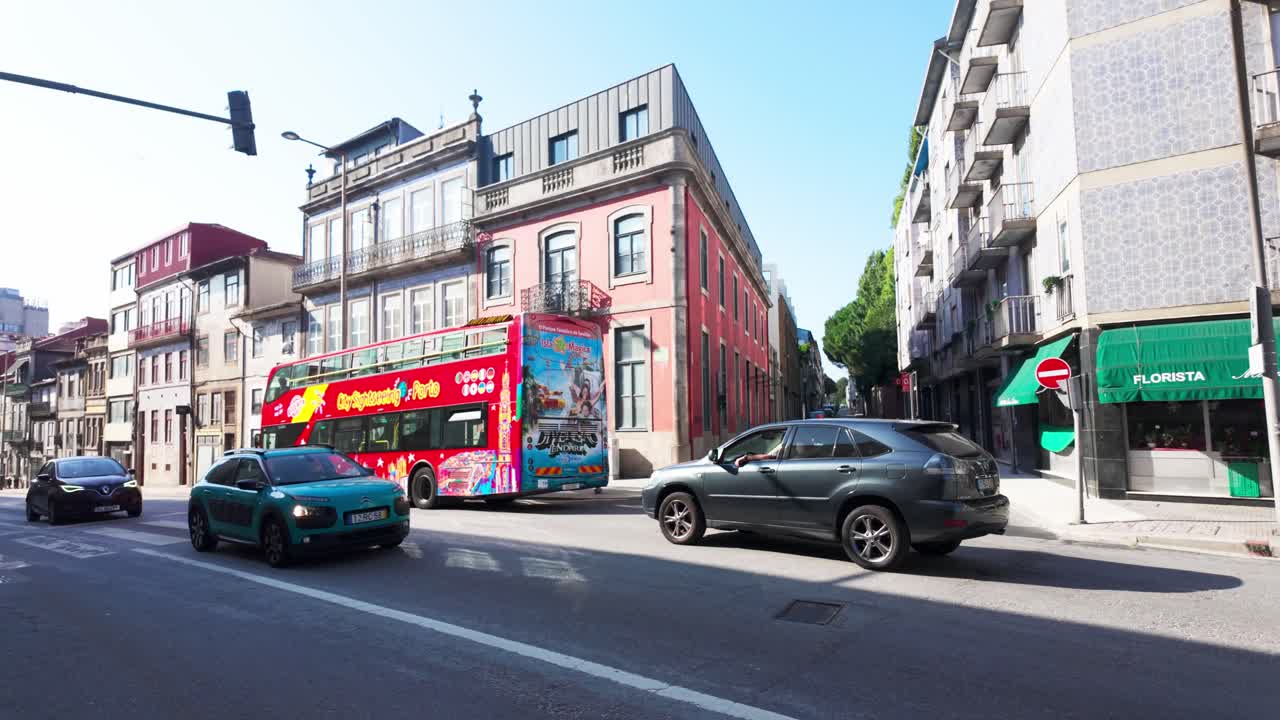Tourists ride a motorbike on a sunny street in Porto, with colorful buses and historic buildings