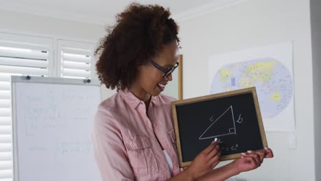mixed race female teacher standing at a whiteboard giving an online lesson to camera