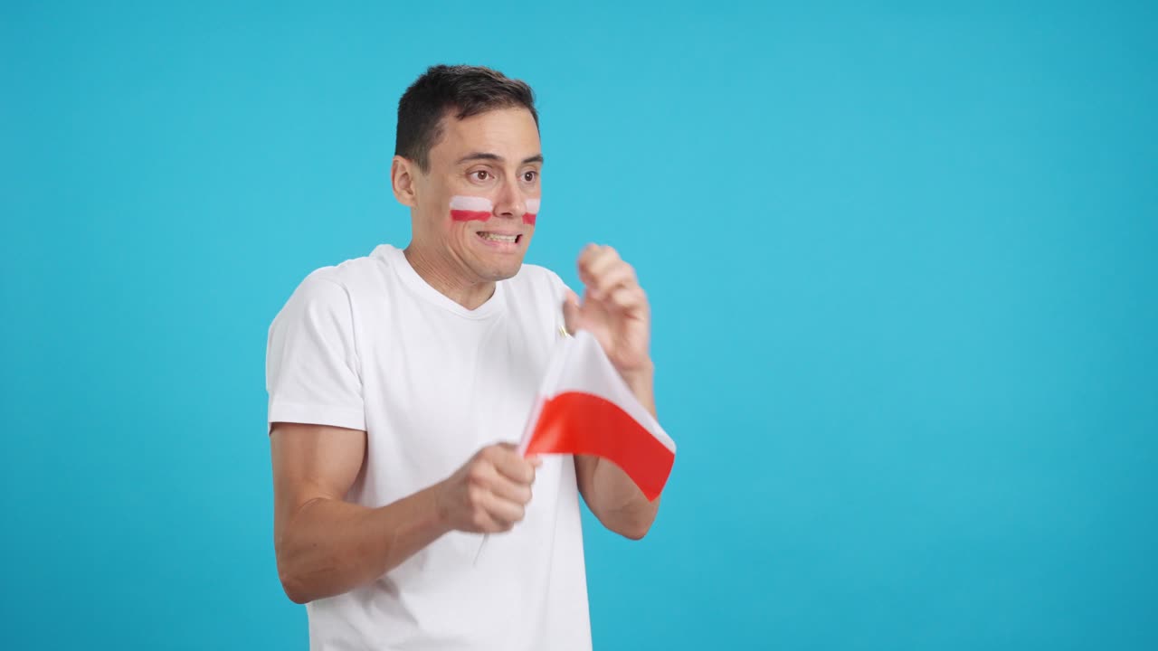 Nervous man cheering for Poland during a match looking away