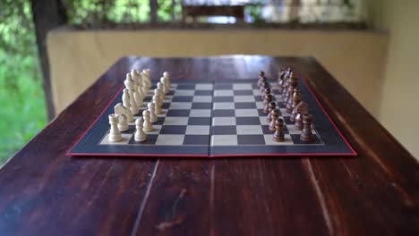 Arranged-Chess-Pieces-On-Chessboard-On-Wooden-Table