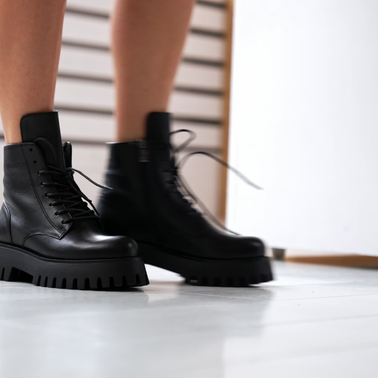 Unrecognized lady with bare legs wearing stylish fashionable boots on tractor soles. Footwear demonstration in studio. Close up