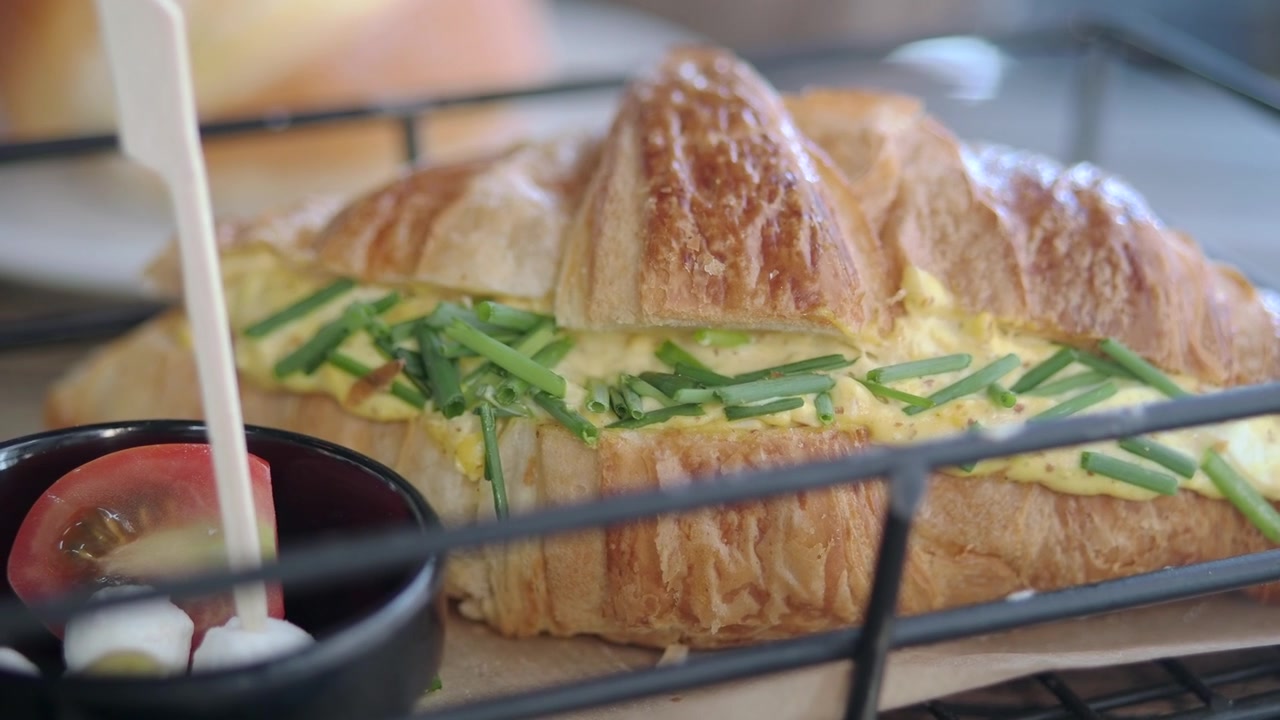 Fersk eggesalat-croissant-sandwich servert i en metallkurv