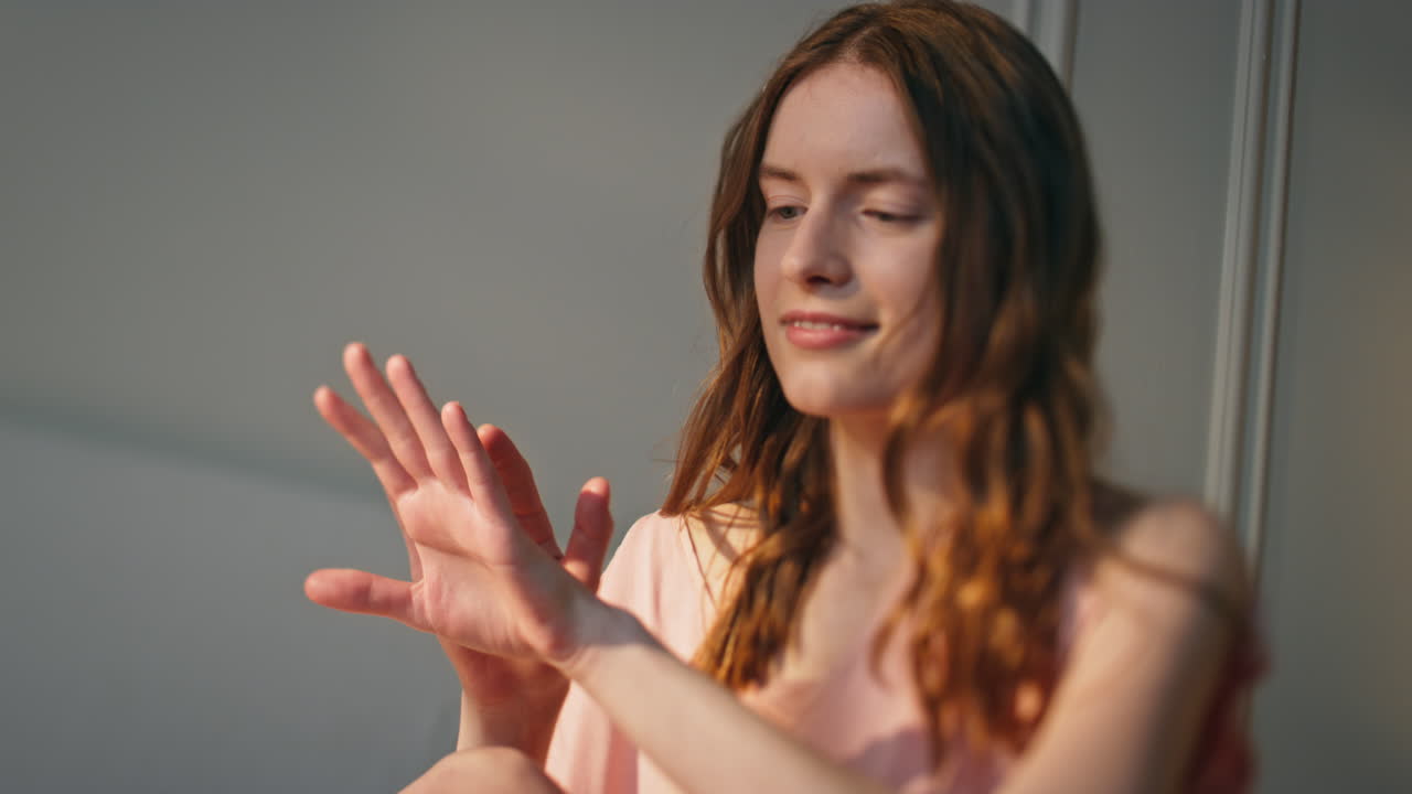 niña en casa sosteniendo un frasco de crema en un primer plano a la luz del sol. mujer joven relajada aplicando