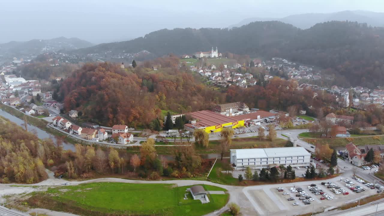 Wide angle dolly in drone shot of the beautiful city, of Celje, Jozefov Hrib-Saint Joseph's hill and the colourful buildings during the day