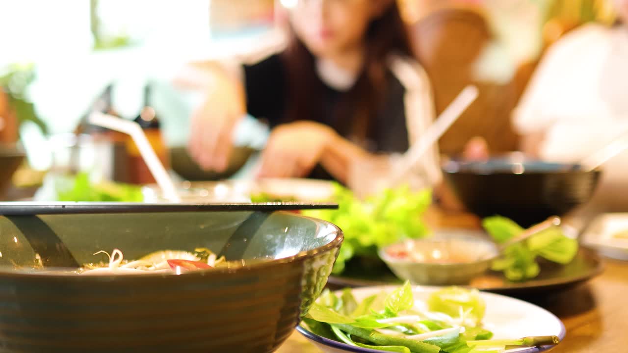 A lively dining scene in a Vietnamese restaurant, capturing vibrant dishes and social interactions under warm lighting